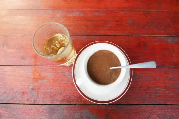 A cup of hot coffe and glass of hot tea on wood table.