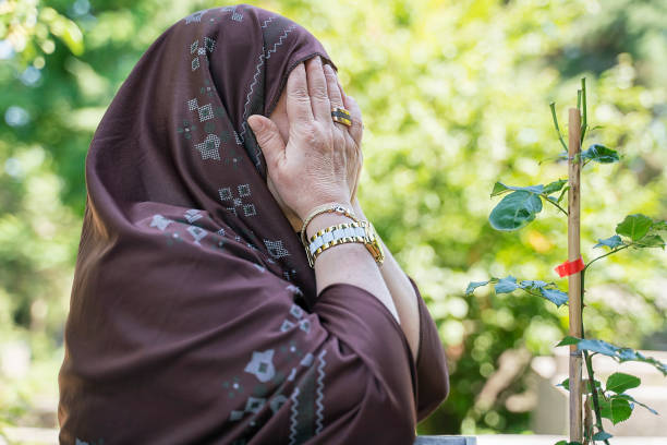 istock Unrecognizable elderly Muslim woman praying in cemetery 1160399414
