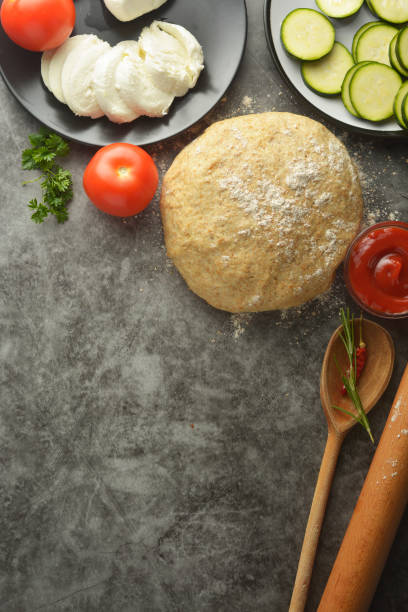 istock Composition with raw dought and fresh ingredients for pizza isolated on dark background. Copy space. Flat lay food ingredients. 1160401665
