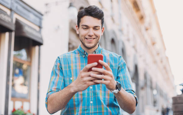 istock Cheerful young man using smart phone in a city 1160409297
