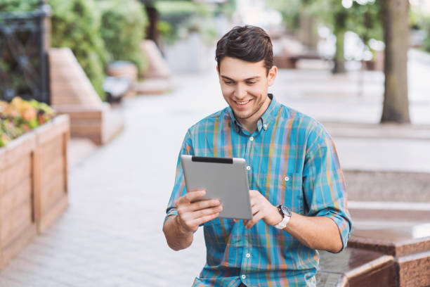 istock Cheerful young man using digital tablet in a city 1160409415