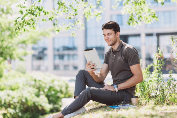 istock Cheerful young man student using digital tablet in a city 1160409418