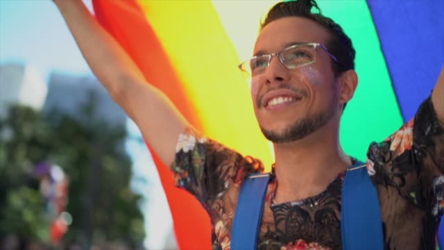 Man walking and waving rainbow flag during LGBTQI parade