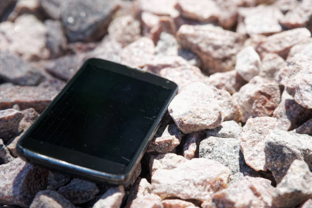 istock Broken cellphone abandoned and lost among the gravel 1160427272
