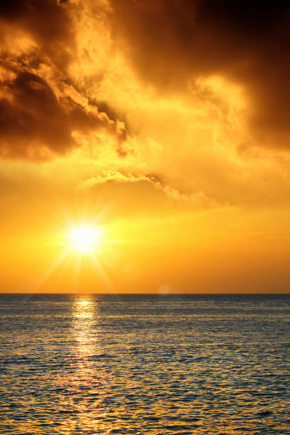 Seascape image of orange color sunset with shiny sea over cloudy sky in Sarasota, Florida
