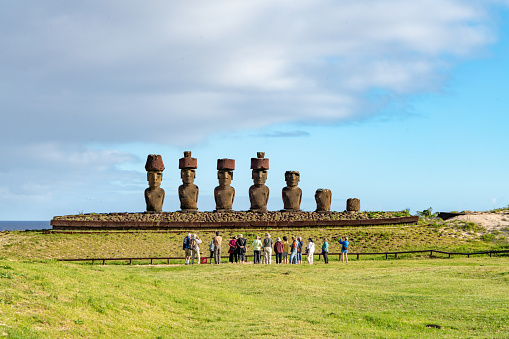 Tourists are watching Moai of Ahu Nau Nau, Easter Island, Chile.