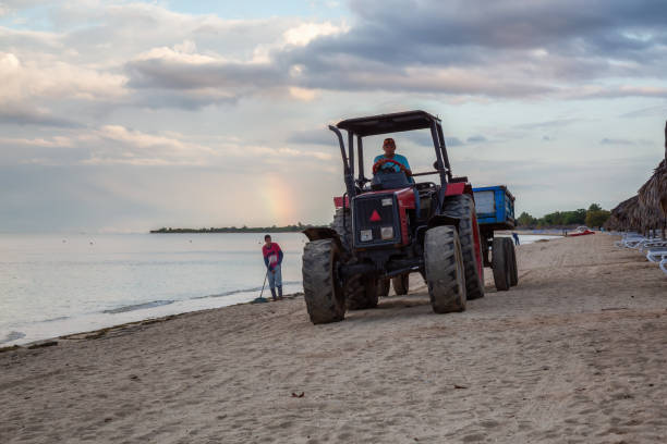 Arrecife, Lanzarote, Canary Islands, Spain - March 8th 2025:  This image captures a specialized beach-cleaning tractor equipped with a sand-sifting device, actively maintaining the shoreline. The robust machine, labeled \