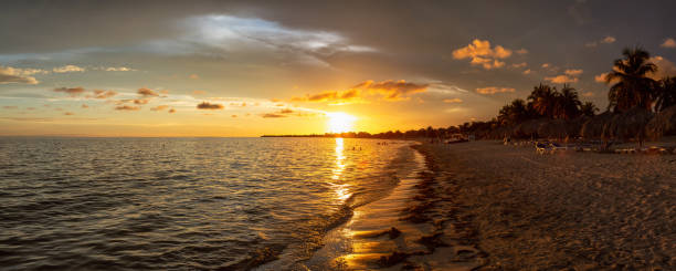 Beautiful Panoramic view of a sandy beach, Playa Ancon, on the Caribbean Sea in Triniday, Cuba, during a dramatic cloudy sunset.