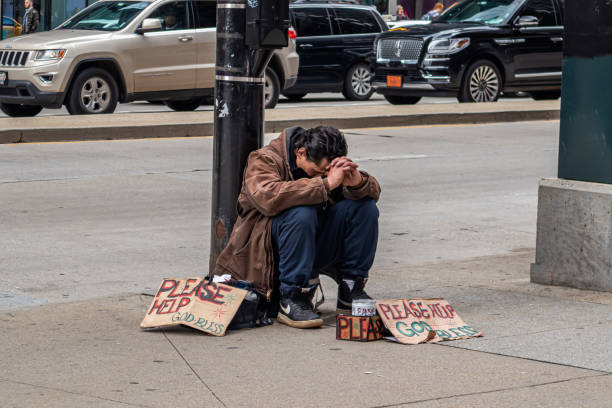 USA, Chicago, Illinois. May 9, 2019. Homeless man sitting on the roadside and cardboard signs asking for help, downtown