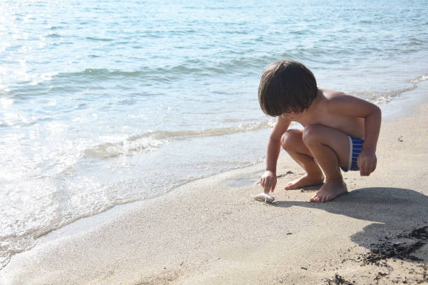 istock Boy play with a little fish on the beach 1160442242
