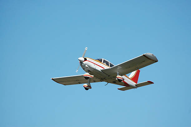 Red airplane biplane with piston engine flies and makes turn in cloudy sky