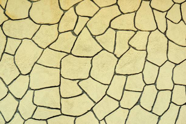 The plastered wall with an abstract mesh mosaic pattern of monotonous yellow color for the textured background or for wallpaper.