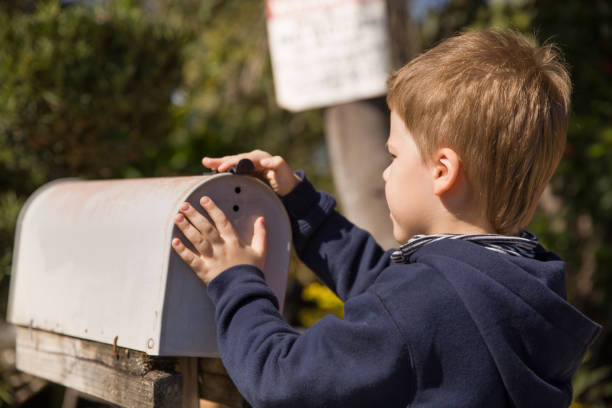 istock School boy opening a post box and checking mail. Kid waiting for a letter, checking correspondence and looking into the in the metal mailbox. 1160454884