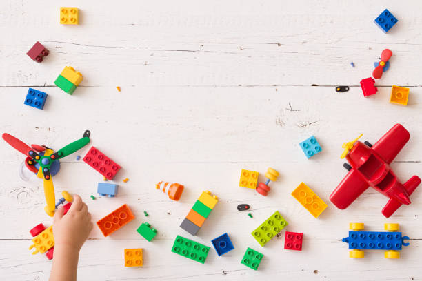 vista superior na mão da criança que joga com os tijolos plásticos da multi-cor na tabela. criança que tem o divertimento e a construção fora dos tijolos brilhantes do construtor. aprendizagem precoce. desenvolvendo brinquedos - block child play toy - fotografias e filmes do acervo