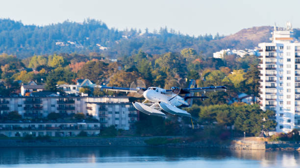 Harbour Air twin otter seaplane, DHC-6 de Havilland, a 19-passenger STOL utility aircraft Victoria, Canada - October 02 2017: Harbour Air twin otter seaplane, DHC-6 de Havilland, a 19-passenger STOL utility aircraft, in flight downtown, with city buildings and landscape in background. de havilland dhc 6 twin otter stock pictures, royalty-free photos & images