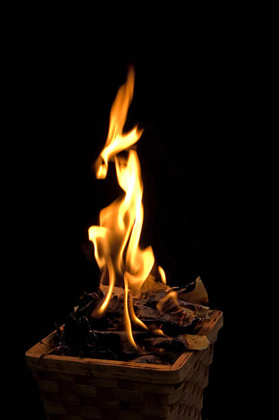 A small wood basket of burning leaves with the flames shown against a black background. Isolated with copy space