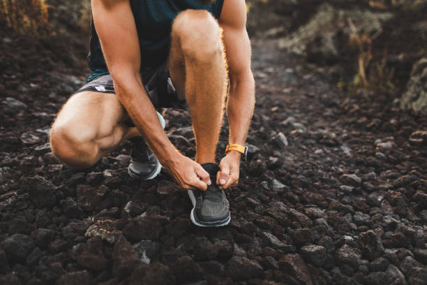 istock Man tying running shoes before trail running outdoors. Close-up 1160478810