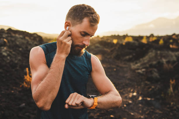 istock Male runner synchronizing wireless earphones with smart watch. Preparing for trail running outdoors at sunrise. 1160478812