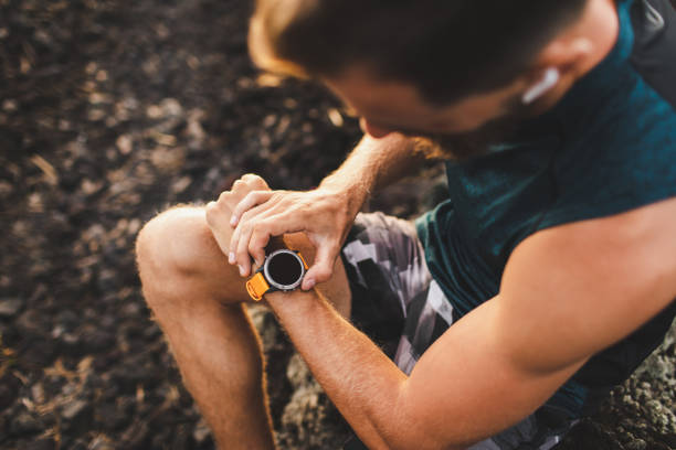 istock Young athletic man using fitness tracker or smart watch before run training outdoors. Close-up photo with dark background. 1160478816