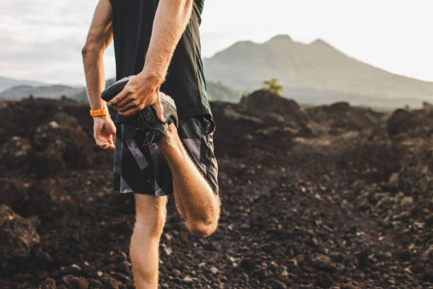 läufer strecken bein und füße und vorbereitung für trail-lauf im freien. aktives und gesundes lifestyle-konzept. bergblick auf dem hintergrund. - aufwärmen stock-fotos und bilder