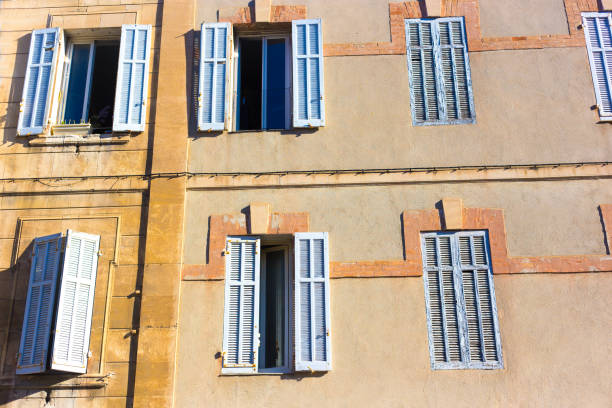 Marseille Architecture: Yellow Sunlit Building Close-Up with Blue Shutters.