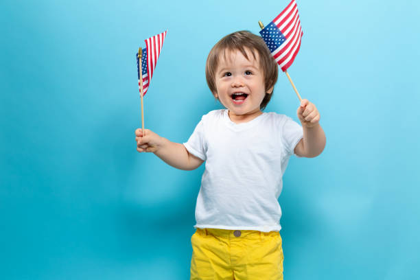 istock Happy toddler boy waving American flags 1160496351