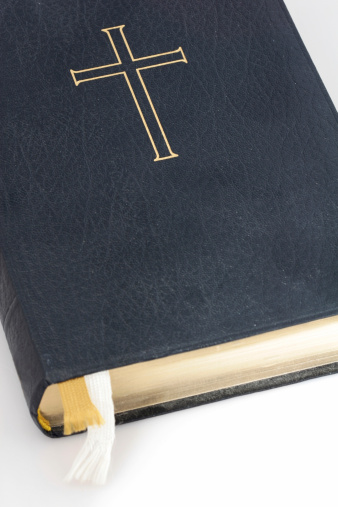 Holy bible, well worn and read, shot on white focus on cross