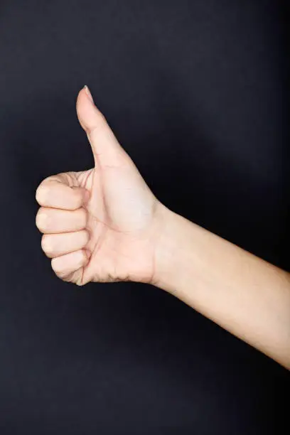 Photo of Thumbs up close up on black background