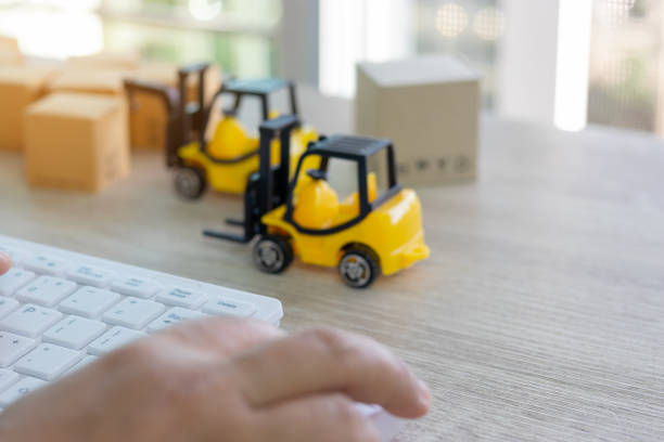 istock Hand using mouse and keyboard and stack of boxes and mini forklift truck nearby. Consumer can buy product directly anywhere anytime from seller using web browser. Online shopping and ecommerce concept 1160513333