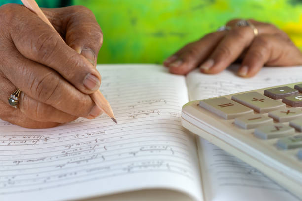 istock Close-up image of elderly asian woman hand holding pencil for compute the Maths problem using Mathematics knowledge and calculator. Education and Lifelong learning concept. 1160513416