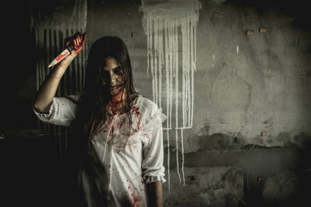 Asian girl dress killer to Halloween festival She's holding a kitchen knife and a big soaked with blood with terrible eyes ready to kill people.