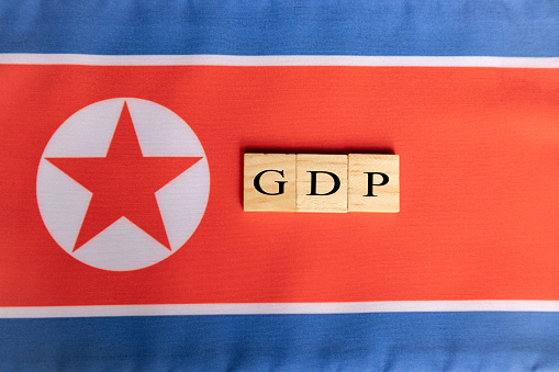 Gross Domestic Product or GDP of North Korea in Wooden block letters on North Korean flag