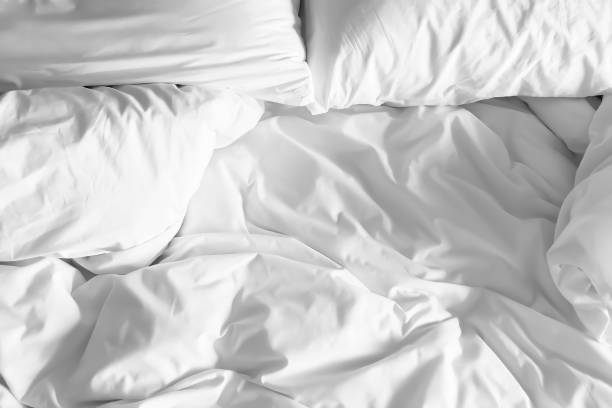 istock Closeup on two soft white pillows and crumpled blanket in bedroom for Valentine backdrop. 1160520698