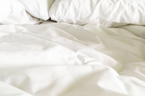 istock Closeup on two soft white pillows and crumpled blanket in bedroom for Valentine backdrop. 1160520710
