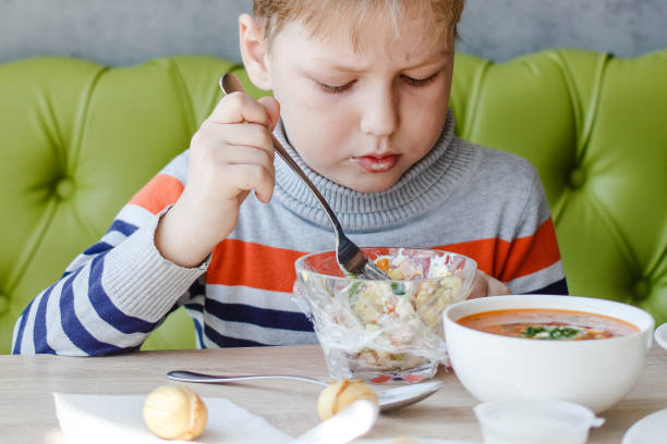 istock little boy eating salad at the table 1160523353