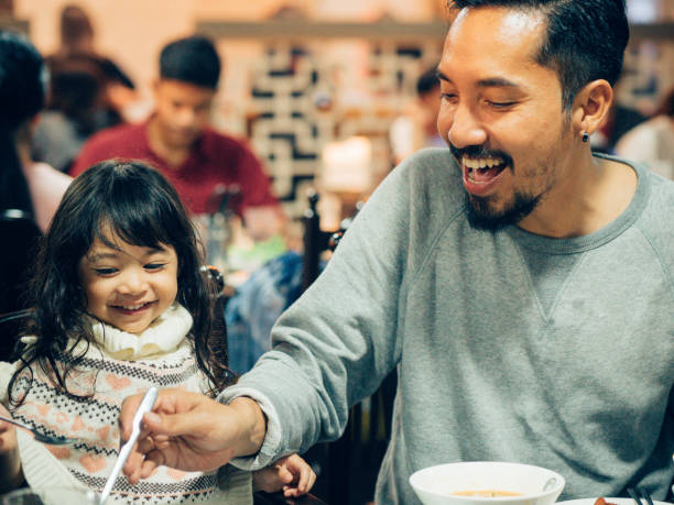 padre hipster asiatico che mangia buffet barbecue coreano con sua figlia nel ristorante. - buffet thai cuisine asian ethnicity food foto e immagini stock