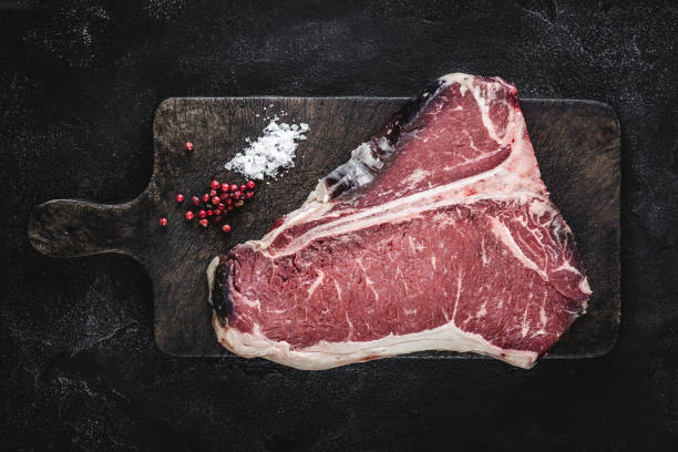 premium dry aged raw t-bone steak on rustic kitchen chopping board - veal t bone steak raw steak imagens e fotografias de stock