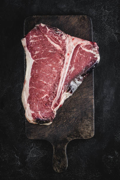 premium dry aged raw t-bone steak on rustic kitchen chopping board - veal t bone steak raw steak imagens e fotografias de stock