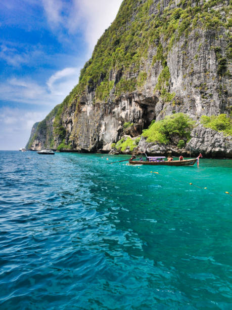 Phi Phi Le, Krabi province, Thailand - May 30 2019:  Phi Phi islands are a top travel destination in the Krabi province, Southern Thailand.  Famed for their clear blue waters and limestone karst islands.  People visit this location in vast numbers daily.  Here we see tour boats taking snorkelers to the island.