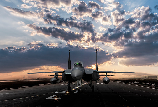 F-15 Eagle jet fighter ready to takeoff on runway at sunset