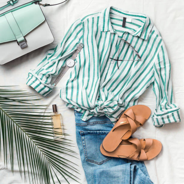 Female fashion clothes flat lay, square Feminine summer fashion composition: striped blouse, slippers, bag, sunglasses, watch, perfume, jeans, palm leaf on white background. Flat lay, top view clothes. Female fashion blog or social media clothing stock pictures, royalty-free photos & images