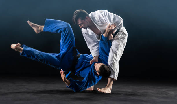 Male Judoka Throwing His Partner To The Ground Male Judoka Throwing His Partner To The Ground judo photos stock pictures, royalty-free photos & images