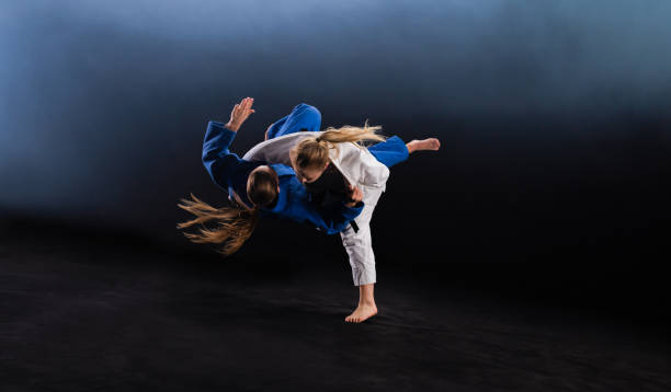 judoka femenina lanzando a su pareja al suelo - judo fotografías e imágenes de stock