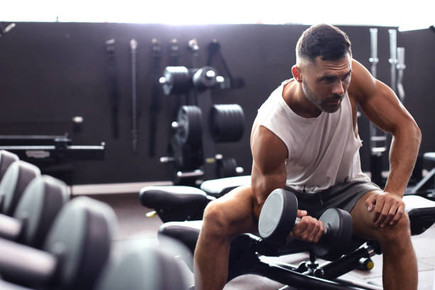 istock Fit and muscular man doing biceps workouts with dumbbells in gym, copy space. 1160537389