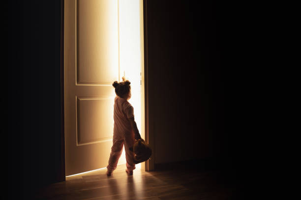 小さな女の子は暗闇の中で光への扉を開く - illuminated leaves ストックフォトと画像