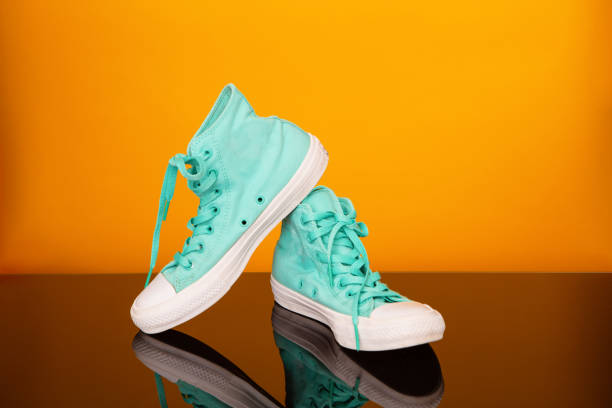 istock Turquoise sneakers on black glass table and yellow background. 1160545961