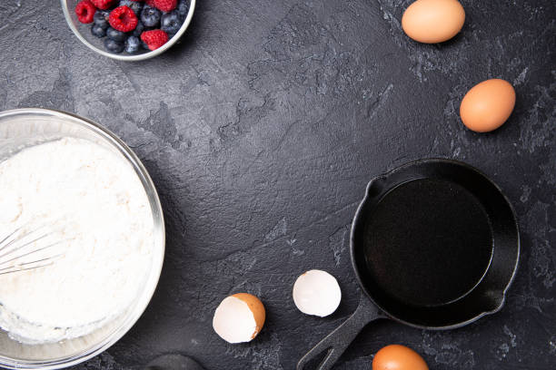 istock Photo of flour, eggs, berries, currants on empty black table. 1160545963