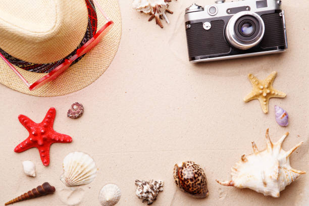 istock Beach accessories - sunglasses, hat and camera on sand witn shells and seastar. 1160545983