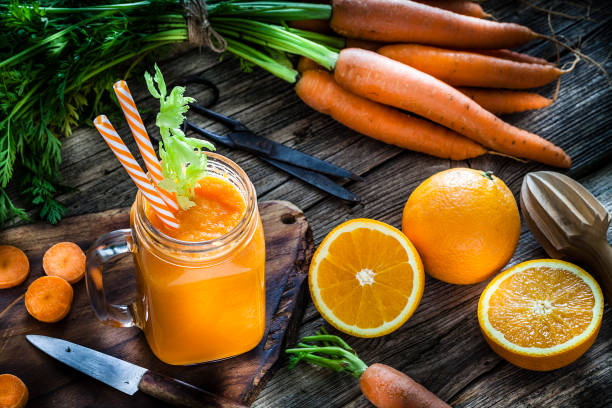 healthy drink: orange and carrot juice on rustic wooden table - orange smoothie imagens e fotografias de stock