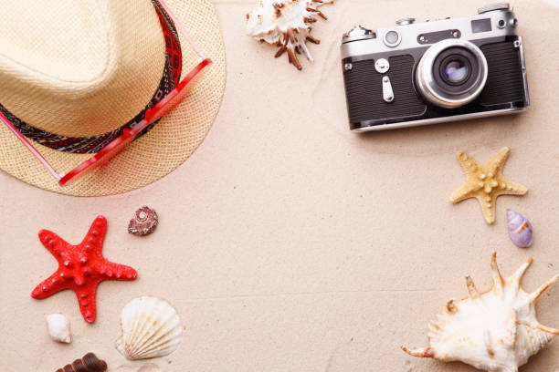 istock Beach accessories - sunglasses, hat and camera on sand witn shells and seastar. 1160546111